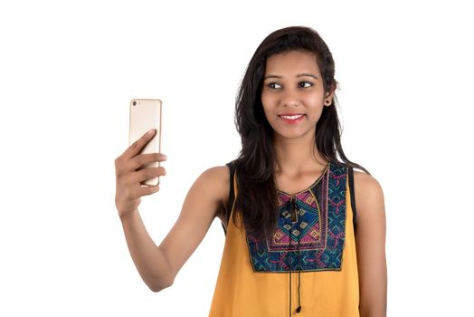 Portrait of a happy young girl using mobile phone isolated over white background