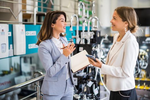 Businesswoman owning small business bath store. She is talking with a customer who is choosing the goods.