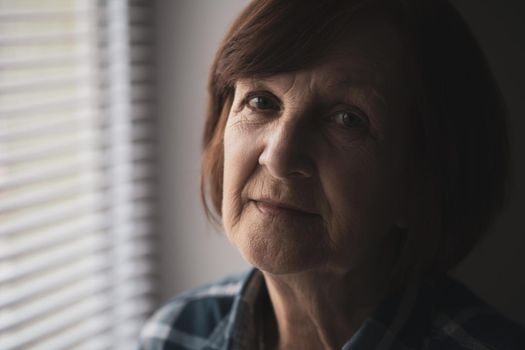 Portrait of lonely senior woman who is sadly looking at camera.