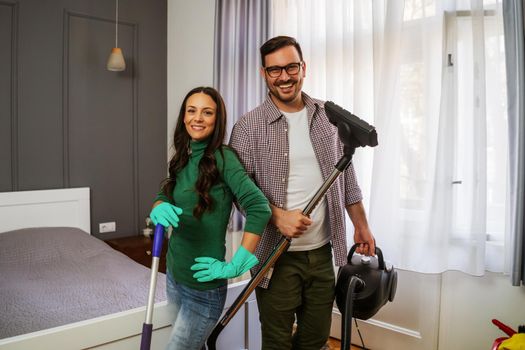 Young happy couple is cleaning their apartment.