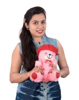 Beautiful young girl holding and playing with a teddy bear toy on a white background.