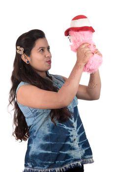 Beautiful young girl holding and playing with a teddy bear toy on a white background.