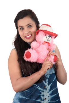 Beautiful young girl holding and playing with a teddy bear toy on a white background.