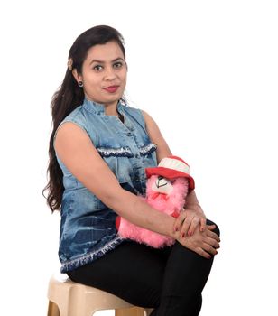 Beautiful young girl holding and playing with a teddy bear toy on a white background.