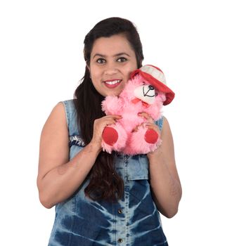 Beautiful young girl holding and playing with a teddy bear toy on a white background.