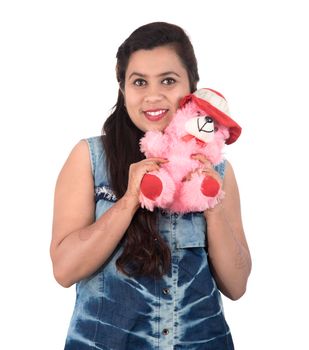 Beautiful young girl holding and playing with a teddy bear toy on a white background.