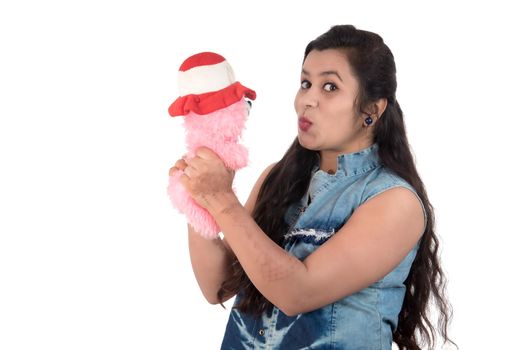 Beautiful young girl holding and playing with a teddy bear toy on a white background.