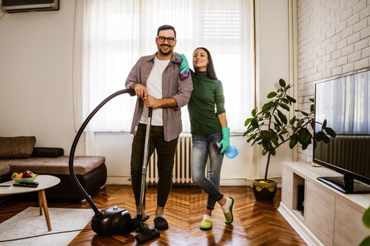 Young happy couple is cleaning their apartment.