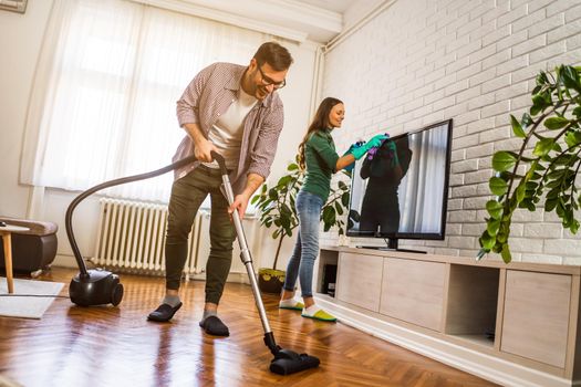 Young happy couple is cleaning their apartment.