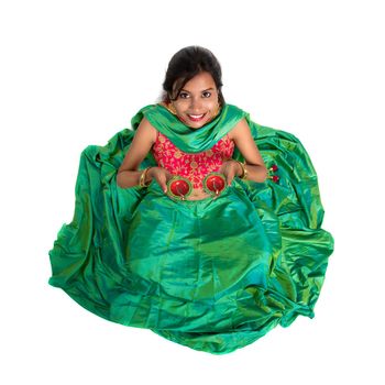 Portrait of a Indian Traditional Girl holding Diya, Girl Celebrating Diwali or Deepavali with holding oil lamp during festival of light on white background