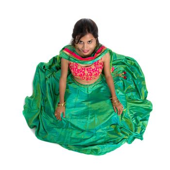 Beautiful Indian traditional girl sitting and posing on white background.