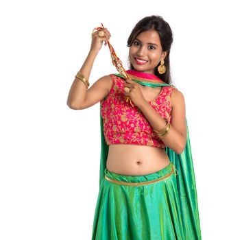 Beautiful girl showing Rakhi on occasion of Raksha bandhan on a white background. Sister tie Rakhi as symbol of intense love for her brother.