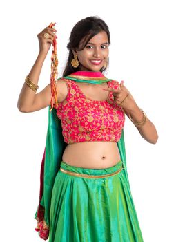 Beautiful girl showing Rakhi on occasion of Raksha bandhan on a white background. Sister tie Rakhi as symbol of intense love for her brother.