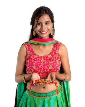 Beautiful girl showing Rakhi on occasion of Raksha bandhan on a white background. Sister tie Rakhi as symbol of intense love for her brother.