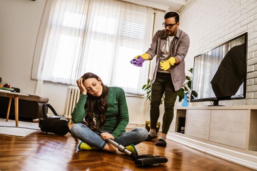 Woman is lazy. Man is telling her to continue cleaning their apartment.