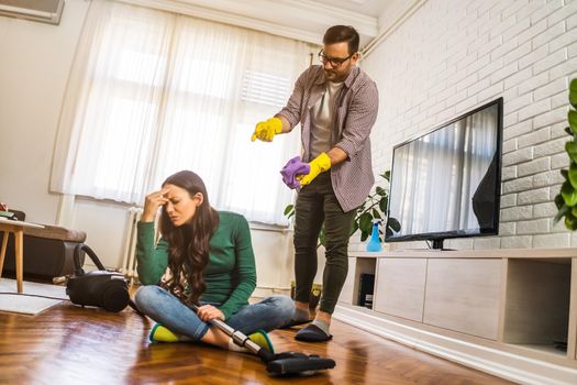 Woman is lazy. Man is telling her to continue cleaning their apartment.