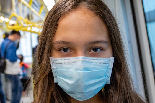 Young Asian American girl wearing surgical mask on subway