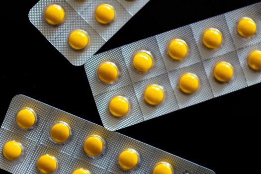 Yellow tablets in blister pack on black background