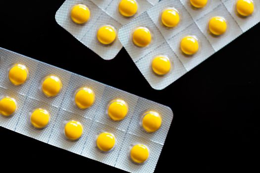 Yellow tablets in blister pack on black background