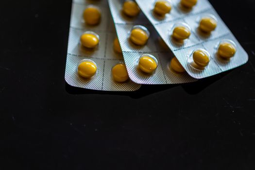 Yellow tablets in blister pack on black background