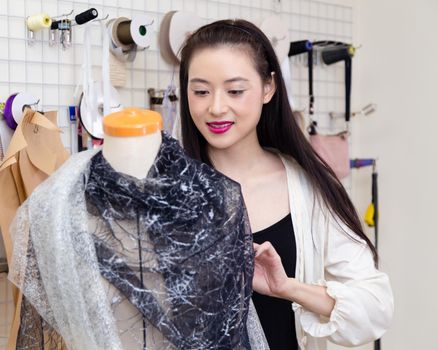 Asian American fashion designer dressing a mannequin