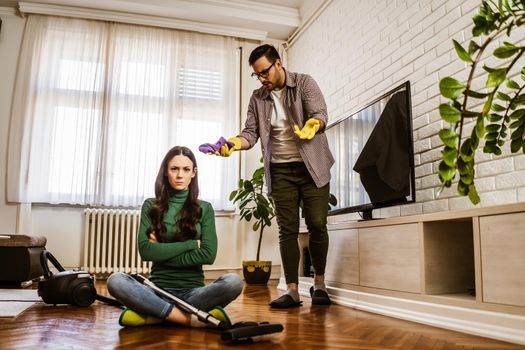 Woman is lazy. Man is telling her to continue cleaning their apartment.