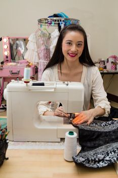 Young Asian American fashion designer at sewing machine