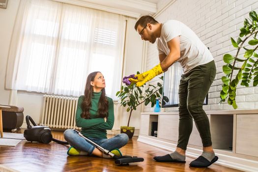 Woman is lazy. Man is telling her to continue cleaning their apartment.