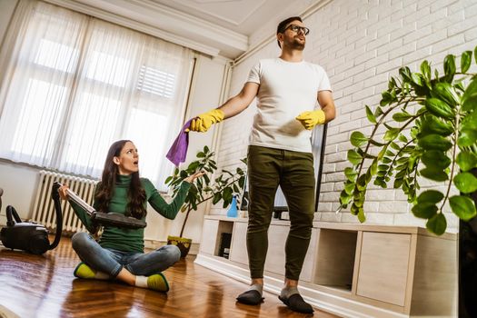 Woman is lazy. Man is telling her to continue cleaning their apartment.