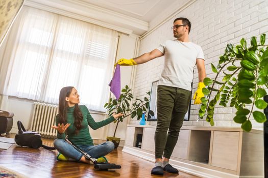 Woman is lazy. Man is telling her to continue cleaning their apartment.