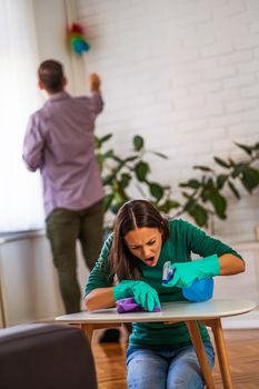 Young happy couple is obsessively cleaning their apartment.