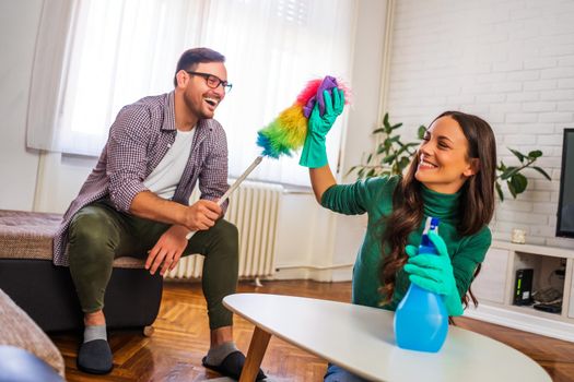 Young happy couple is cleaning their apartment.