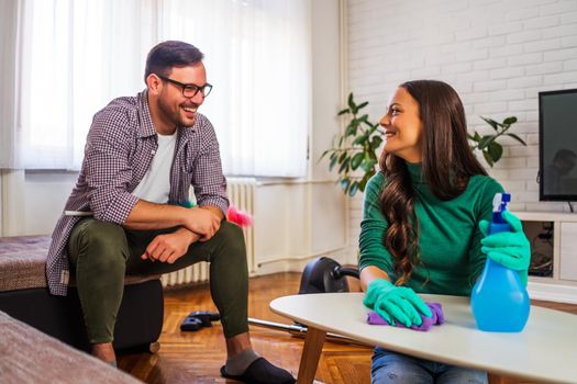 Young happy couple is cleaning their apartment.