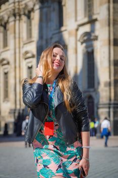 A young beautiful girl walks around the city on excursions. Cheerful, happy laugh.