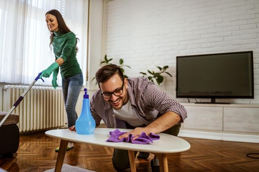 Young happy couple is cleaning their apartment.