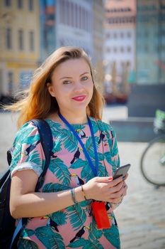 A young beautiful girl walks around the city on excursions. Cheerful, happy laugh.