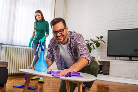 Young happy couple is cleaning their apartment.