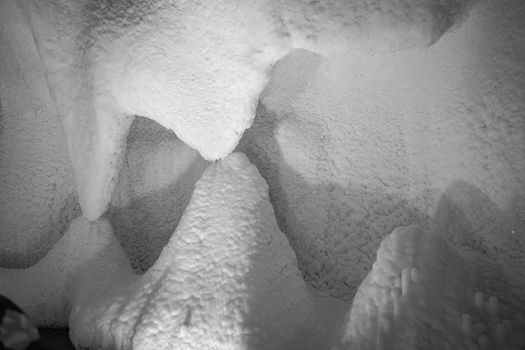 A fabulous artificial ice cave, the walls are covered with snow and illuminated. Frozen ice and cold inside