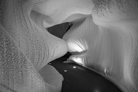 A fabulous artificial ice cave, the walls are covered with snow and illuminated. Frozen ice and cold inside
