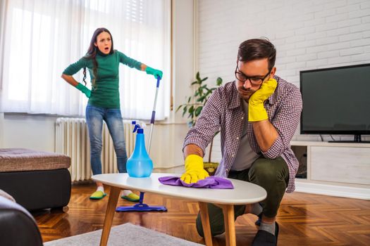 Man is tired of cleaning the apartment. Woman is angry.