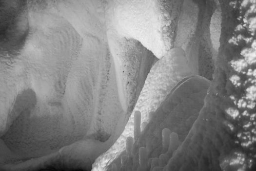 A fabulous artificial ice cave, the walls are covered with snow and illuminated. Frozen ice and cold inside