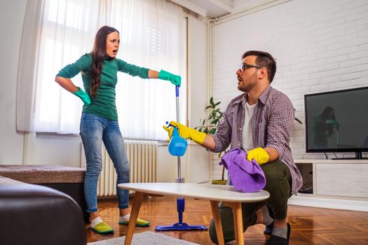 Man is tired of cleaning the apartment. Woman is angry.