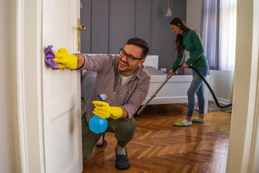 Young happy couple is cleaning their apartment.