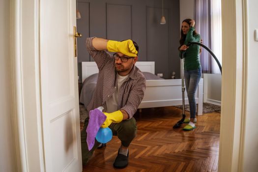 Young couple is cleaning their apartment. They are tired.