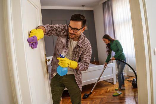 Young happy couple is cleaning their apartment.