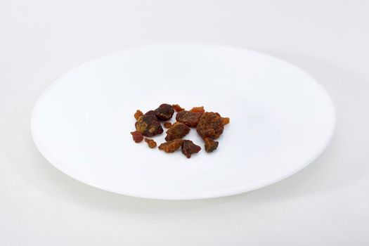 Asafoetida pices on a white plate on a white background