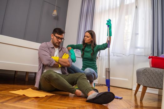 Man is lazy. His wife is telling him to continue cleaning their apartment.