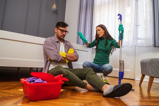 Man is lazy. His wife is telling him to continue cleaning their apartment.