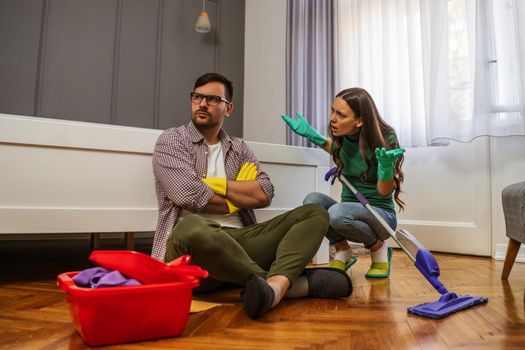 Man is lazy. His wife is telling him to continue cleaning their apartment.