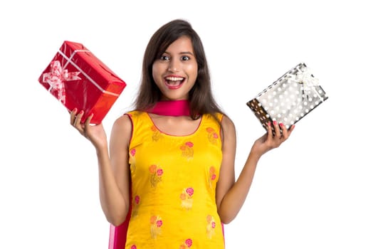 Portrait of young happy smiling Indian Girl holding gift boxes on a white background.